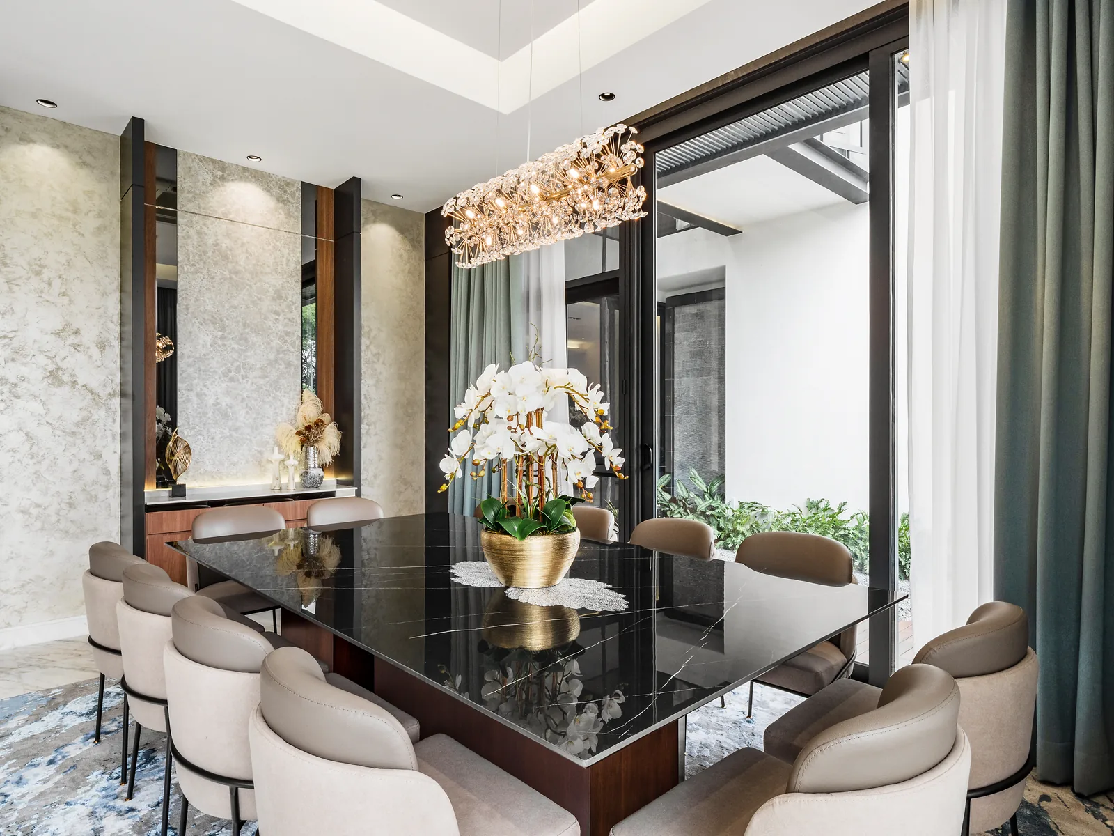 Dining area with a black stone table and a floral chandelier beside a full-height window, Kelana Jaya bungalow, Selangor, Malaysia, by Blaine Robert Design