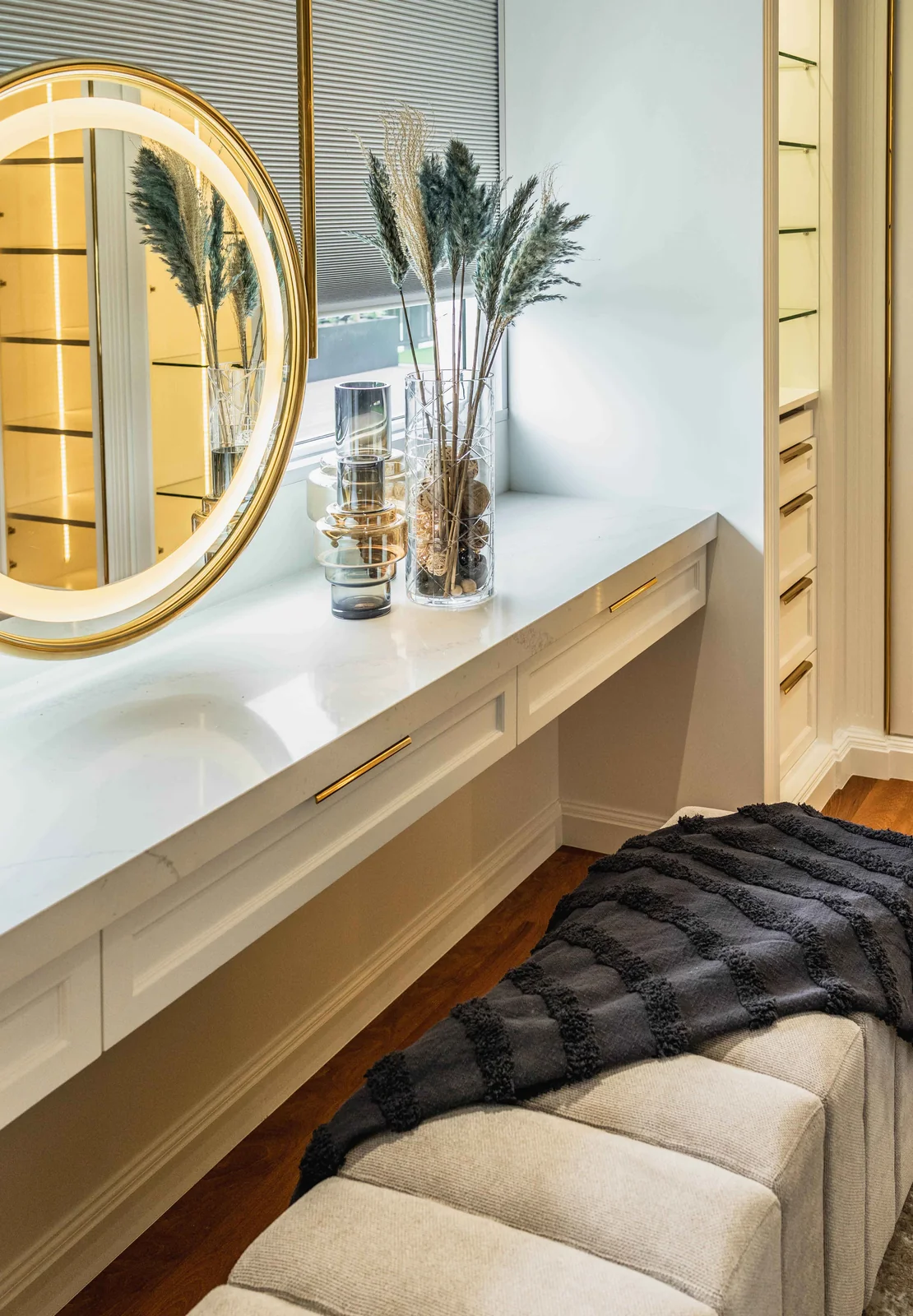Dressing table under a backlit round mirror with an upholstered bench inside a walk-in wardrobe, Eco Spring, Johor Bahru, Malaysia, by Blaine Robert Design