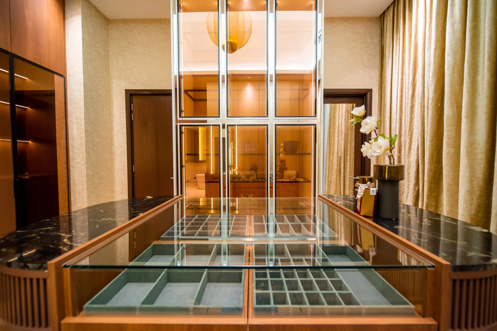 Walk-in wardrobe island with a glass top over velvet-lined jewellery drawers and gold-framed glass cabinets, Bangsar, Kuala Lumpur, by Blaine Robert Design